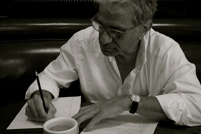 Мужчина пишет ручкой на чашке с часами на запястье руки.